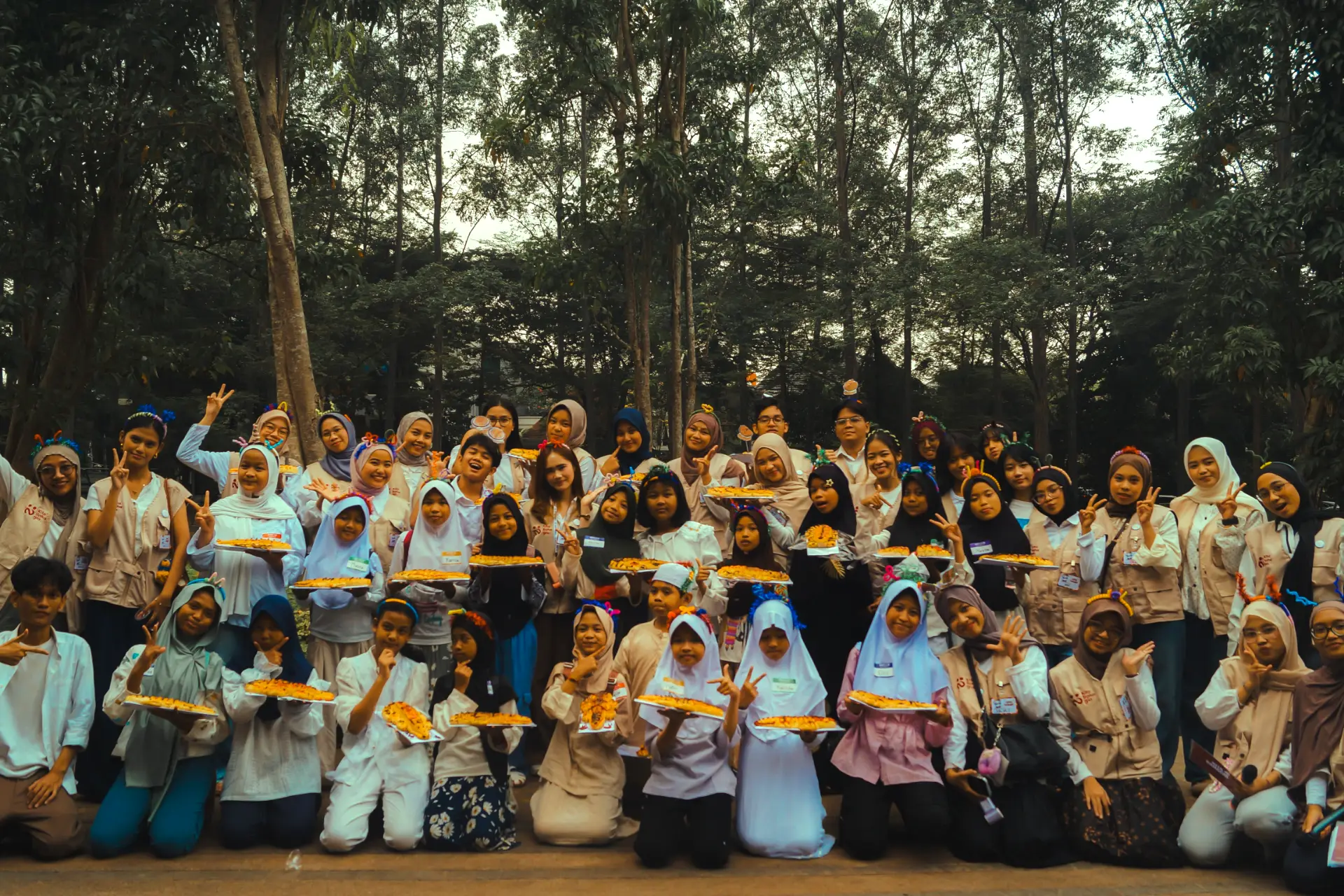 Relawan Kita Bahagia berfoto bersama adik-adik sambil memegang hasil masakan